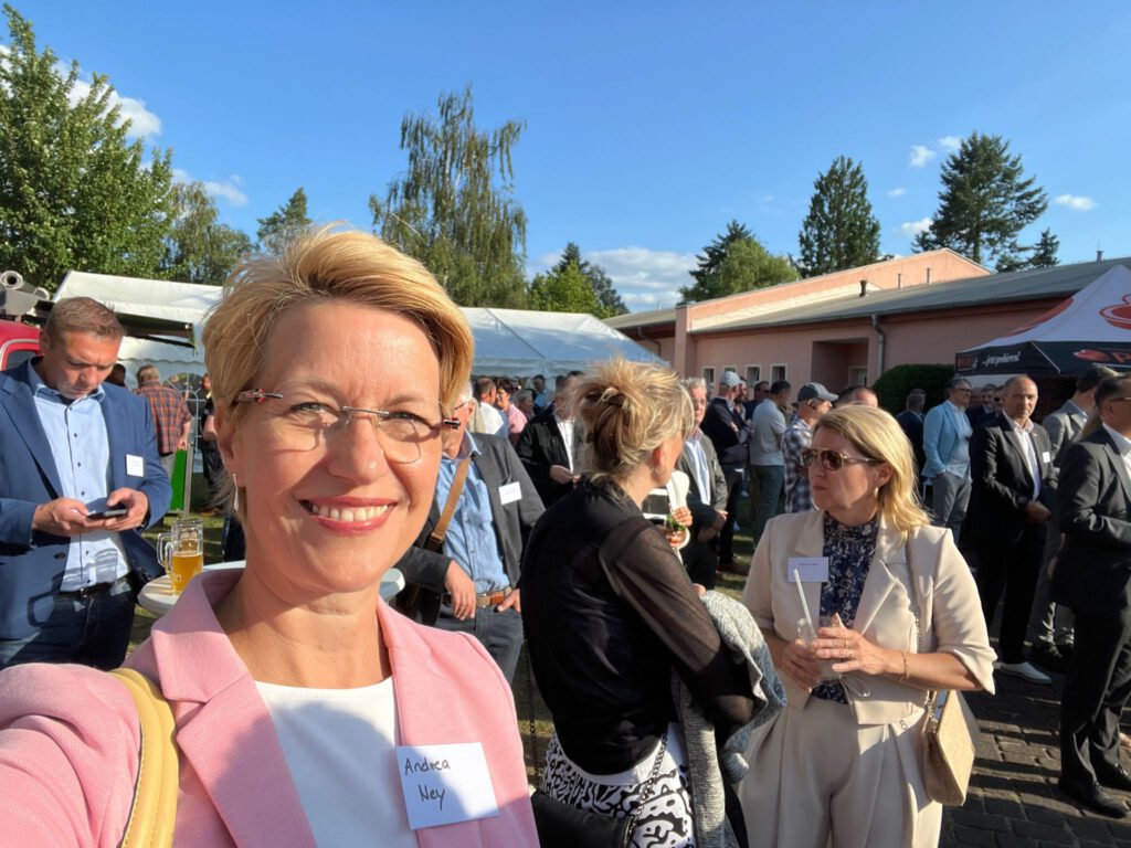 Andrea Ney beim Sommerfest der Handwerkskammer in Caputh – lächelnd in die Kamera, umgeben von Unternehmerinnen und Unternehmern am Schwielowsee.