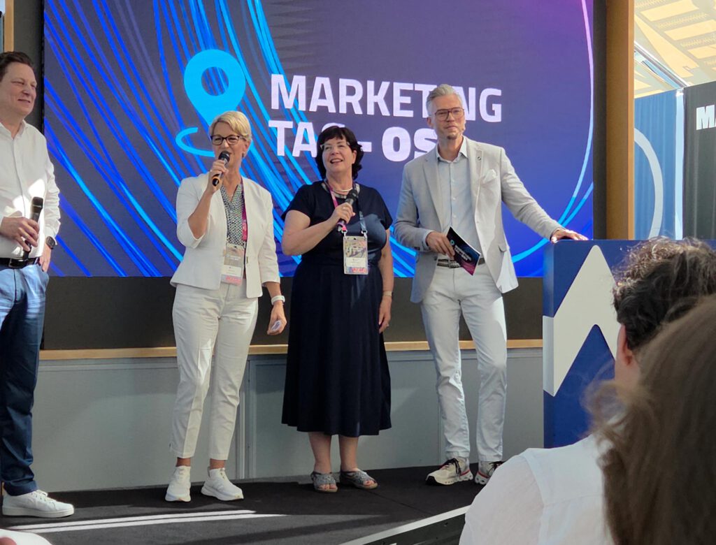 Foto vom MarketingTag Ost 2026 in Leipzig mit Moderation und Austausch auf der Bühne. Das Bild begleitet einen Beitrag der AGENTUR SCHWEIGER zu Markenführung, KI, regionalen Marken, Employer Branding, Positionierung und der Wirkung starker Marketingnetzwerke.